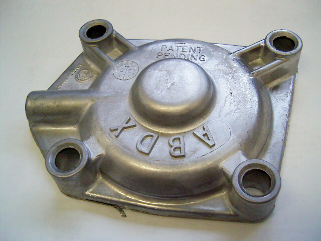 Carpenter Die Casting Metal engine or machine part with four bolt holes, labeled "A", "B", "D", "X", and "PATENT PENDING" lettering on the top surface.