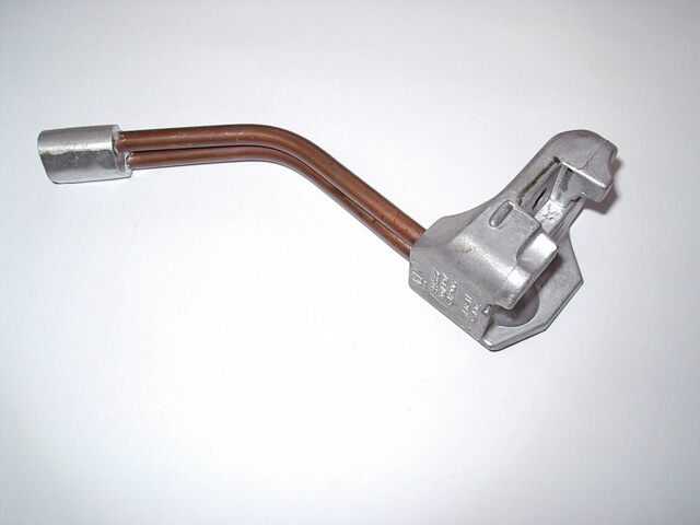 Carpenter Die Casting A metal automotive part with two bent copper tubes attached to a silver cast component, placed on a white background.