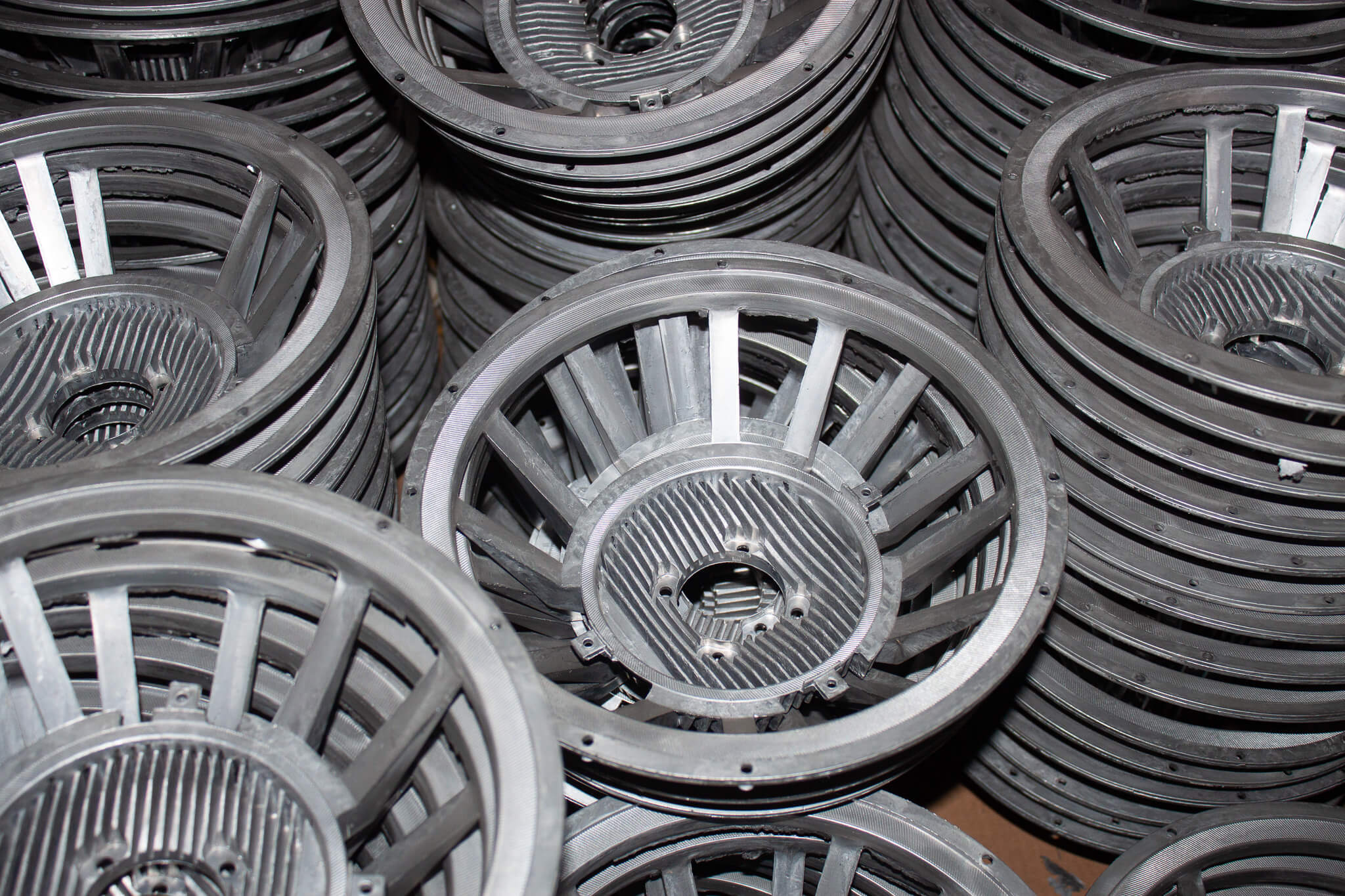 Carpenter Die Casting Stacks of metal industrial fan housings are arranged in a pile, showing their circular frames and radial support structures.